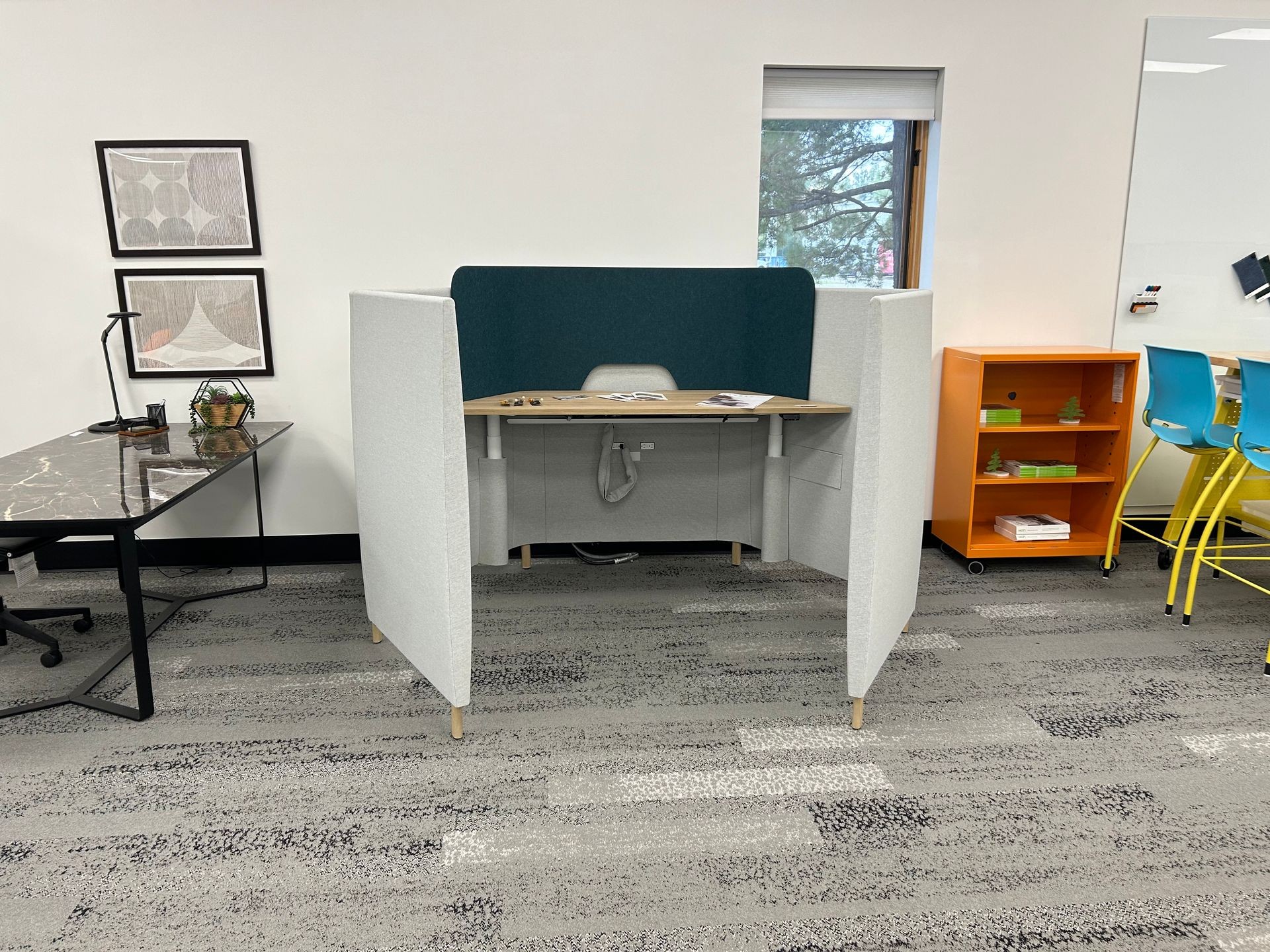 Modern office with a small cubicle, desk, chairs, and colorful decor.